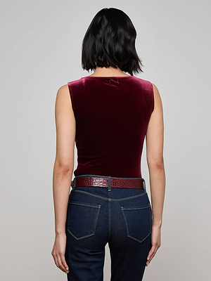Seen from behind against a plain light gray background, a person with short black hair wears the L’AGENCE Molly Velvet Bodysuit in burgundy, paired with dark blue jeans and a textured brown belt.