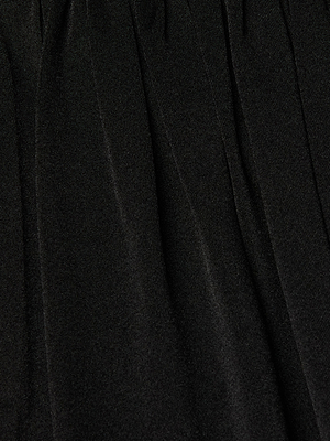 Close-up of black pleated fabric from the Akari Bodysuit, showcasing soft vertical folds and a subtly textured liquid jersey finish.