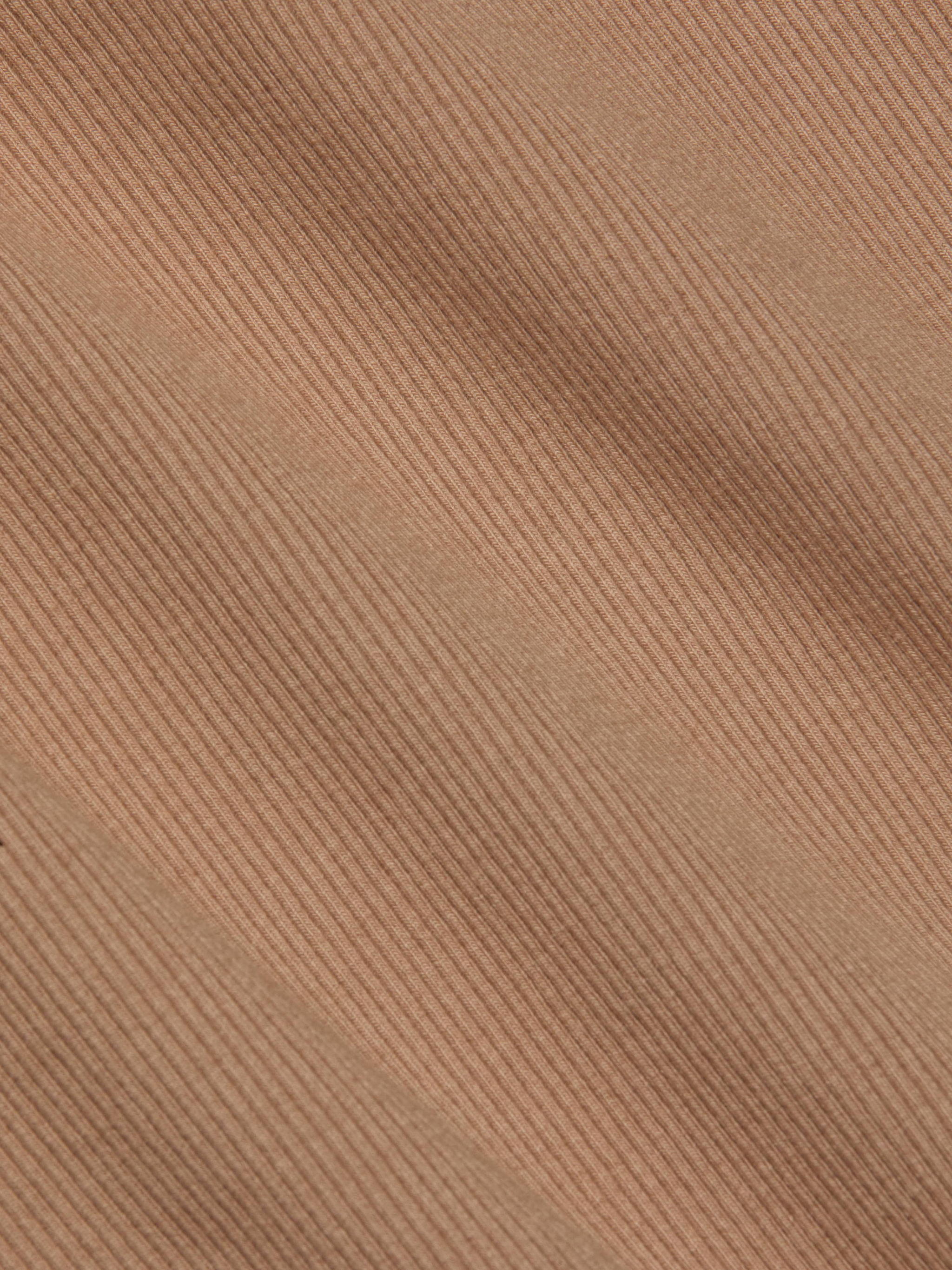 Close-up of the Nica Scoopneck Bodysuit in light brown corduroy, showcasing its diagonal ridges and soft, textured material. The image highlights the stretch rib weave pattern and detail, making it an ideal base layer.