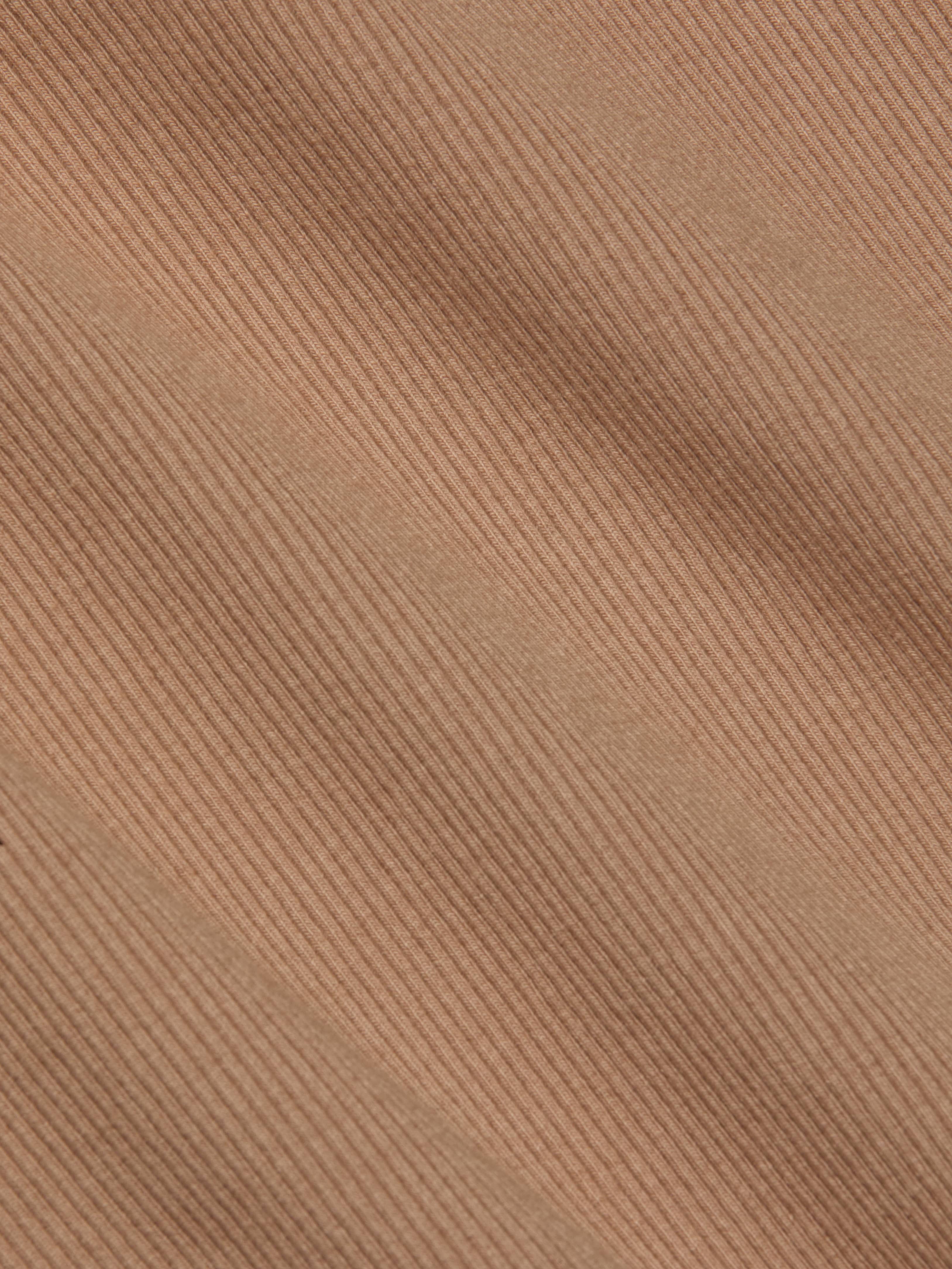 Close-up of the Nica Scoopneck Bodysuit in light brown corduroy, showcasing its diagonal ridges and soft, textured material. The image highlights the stretch rib weave pattern and detail, making it an ideal base layer.