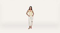 A woman stands against a plain white background, wearing a yellow tank top, white ripped jeans, and light-colored sandals.
