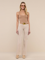 A woman stands facing forward against a plain white background, wearing sunglasses, the Nica Scoopneck Bodysuit in sleeveless camel stretch rib, beige wide-leg pants with a belt, and tan shoes.