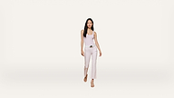Woman with long dark hair wears a light pink sleeveless top, white pants with a belt, and beige sandals, walking forward against a plain white background.