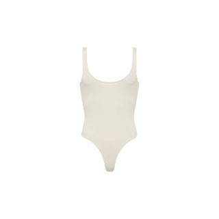 The Nica Scoopneck Bodysuit is a sleeveless, off-white piece made from soft stretch-cotton, featuring a scoop neckline and high-cut legs. Shown against a white background, it’s perfect as a versatile layering essential.