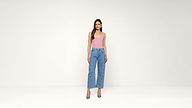 Woman standing against a plain white background, wearing a sleeveless pink top, high-waisted blue wide-leg jeans, and blue heels, with long hair down.
