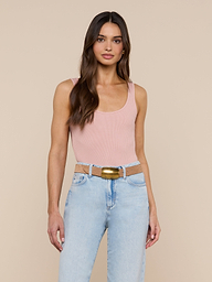 Woman with long brown hair wearing a light pink Nica Scoopneck Bodysuit with a sculpted fit, light blue high-waisted jeans, and a wide tan belt, standing against a plain white background.