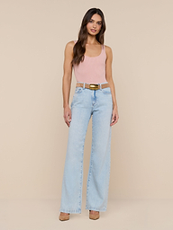 A woman stands against a plain white background, wearing a light pink Nica Scoopneck Bodysuit with a sculpted fit, light blue high-waisted wide-leg jeans, and beige high heels.