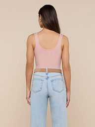 A person with long brown hair is wearing the Nica Scoopneck Bodysuit in pink and light blue sculpted-fit jeans, standing facing away against a plain background.