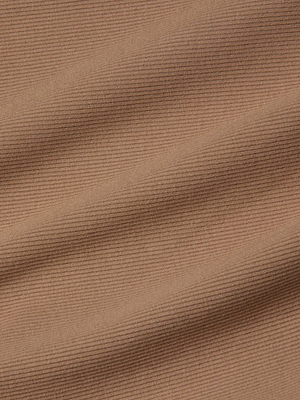 Close-up of light brown corduroy fabric with fine vertical ridges and gentle folds, highlighting its soft texture and pattern—reminiscent of the sculpted fit of the L'AGENCE Nica Scoopneck Bodysuit.