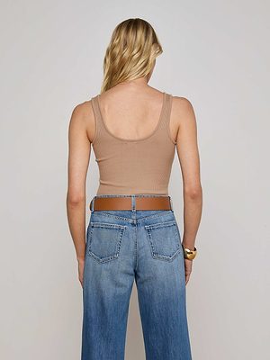 A person with long blonde hair, seen from behind, wears a beige L'AGENCE Nica Scoopneck Bodysuit and blue jeans against a plain light background.