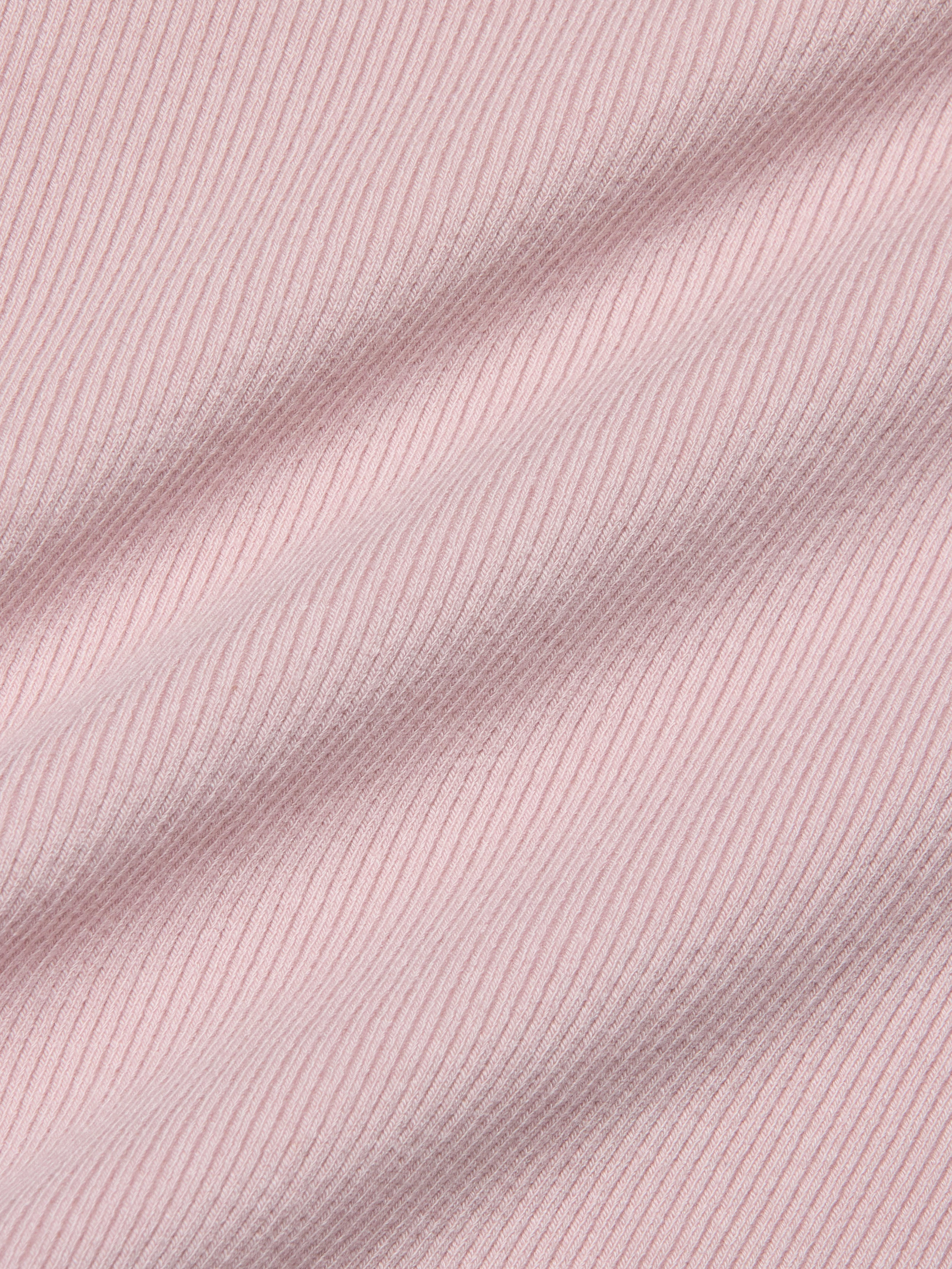 Close-up of the Nica Scoopneck Bodysuit in light pink, featuring high-stretch rib fabric with soft shadows emphasizing its texture and gentle folds.