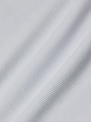 Close-up of a white ribbed fabric with diagonal lines and fine ridges, highlighting the soft texture and shadows of the Nica Scoopneck Bodysuit base layer.