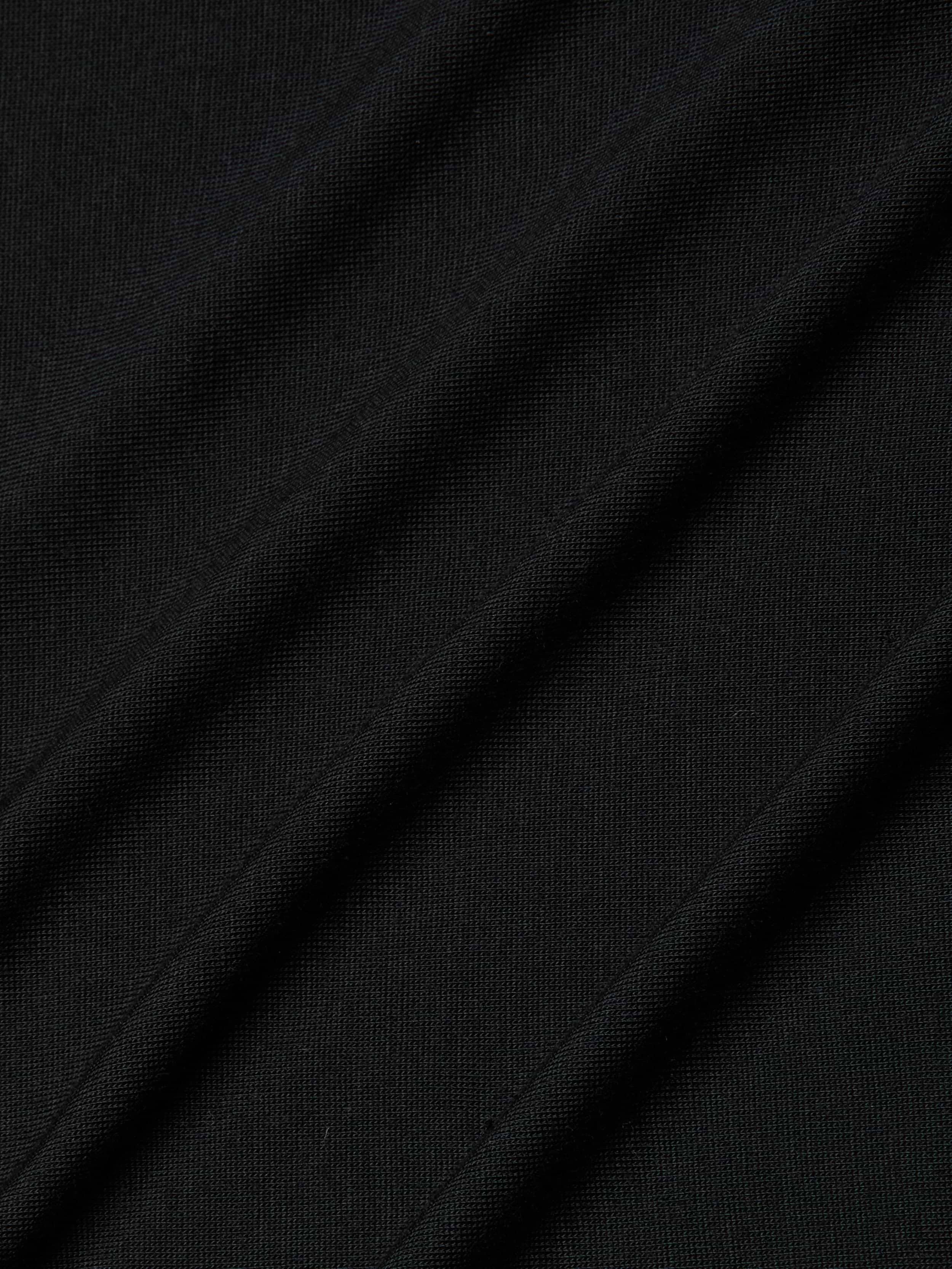 Close-up of the Remy Tee in black micro modal jersey fabric with diagonal folds and visible texture, highlighting its fine knit pattern and subtle shadows for a relaxed fit.