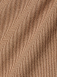 Close-up of the Adira Tank’s light brown ribbed fabric, with diagonal folds and fine textured lines that highlight the intricate pattern and soft surface of this essential piece.