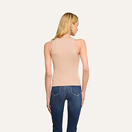 On voit de dos une personne aux longs cheveux blonds, vêtue du débardeur Adira à encolure dégagée en jersey de coton stretch côtelé et dun jean bleu, se tenant debout devant un fond beige uni.