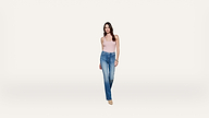A woman wearing a light pink tank top, blue jeans, and beige shoes stands against a plain white background, facing forward.