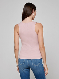 A woman with long brown hair stands facing away, wearing the Adira Scoopneck Tank in light pink and blue jeans against a plain light background.
