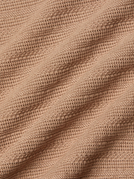 Close-up of the Adira Scoopneck Tank in peach-colored organic cotton, featuring a ribbed, textured pattern in diagonal lines. The soft material is slightly stretched, highlighting the details of the individual knit stitches.