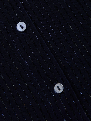Close-up of the Indiana Blouse by L'AGENCE in navy fabric with subtle metallic pinstripes, featuring two round, light buttons engraved with letters around their edges.