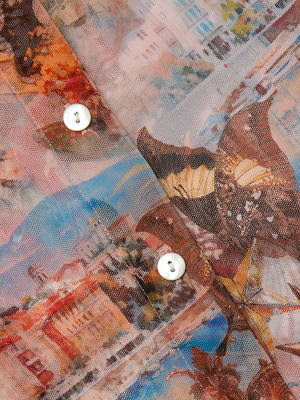 Close-up of the Indiana Mesh Blouse by L'AGENCE, featuring white buttons and a vibrant abstract cityscape with butterfly travel postcard print. The sheer texture and intricate design details are clearly visible.