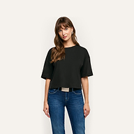A person wearing a plain, black, oversized cropped Daria Oversized Cropped Tee made of Supima cotton with a relaxed fit and blue jeans.