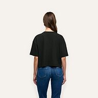 Back view of a person wearing a black Daria Oversized Cropped Tee made of Supima cotton and relaxed-fit blue jeans.