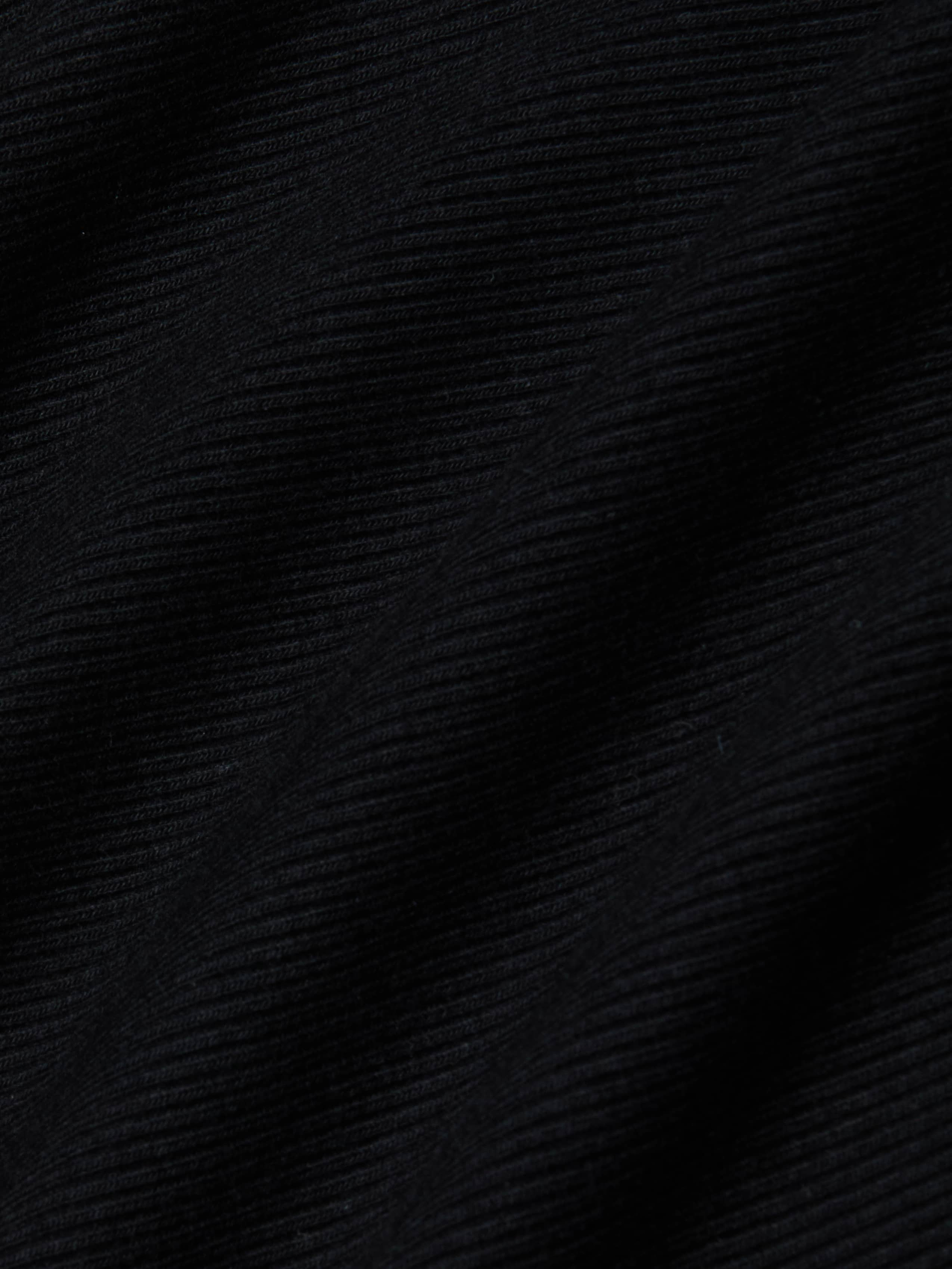 Close-up of the black ribbed fabric from the Evelyn Off-The-Shoulder Bodysuit, showcasing horizontal textured lines and gentle folds that cast subtle shadows and add depth to the stretch cotton modal material.