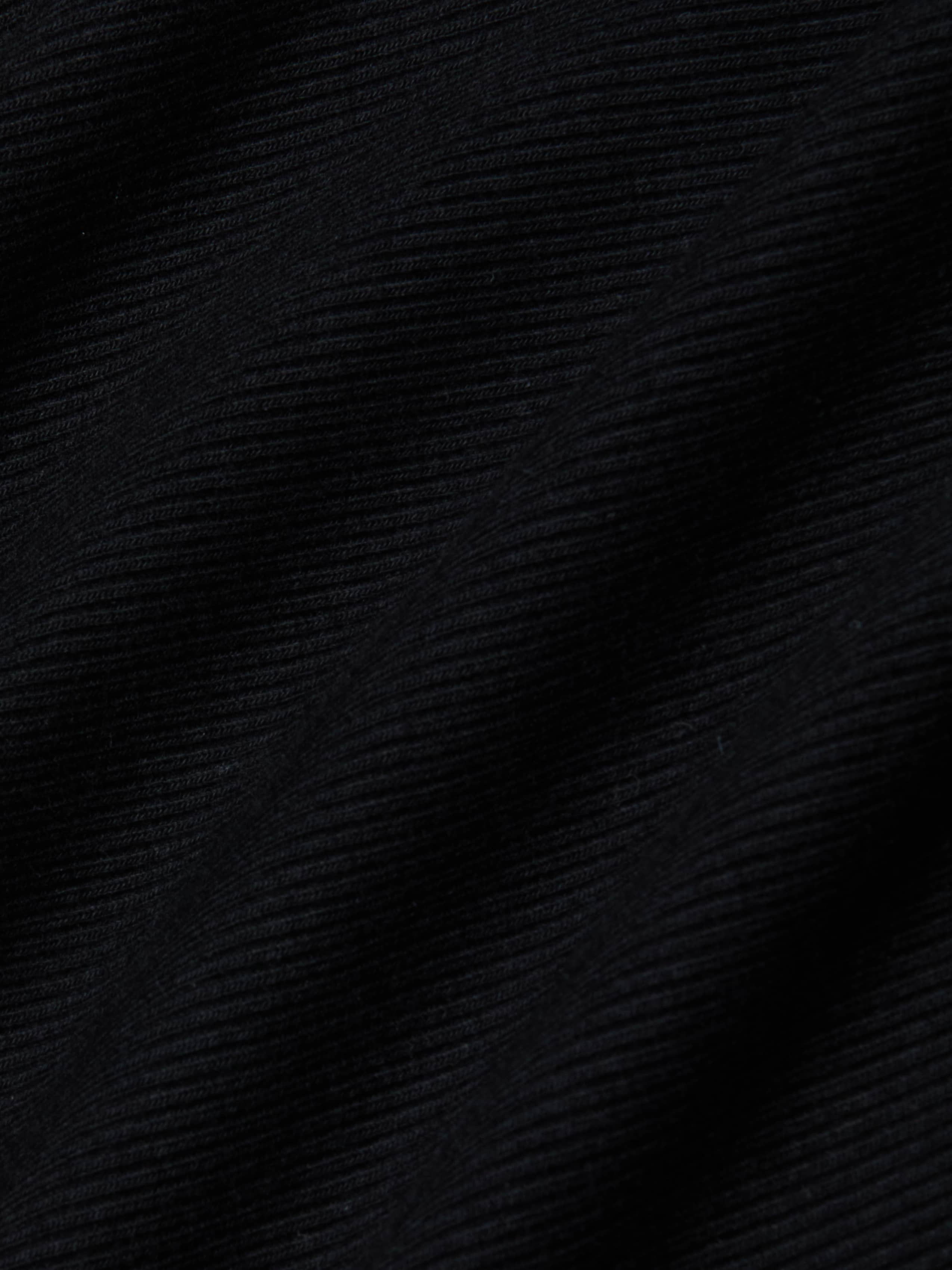 Close-up of the black ribbed fabric from the Evelyn Off-The-Shoulder Bodysuit, showcasing horizontal textured lines and gentle folds that cast subtle shadows and add depth to the stretch cotton modal material.