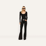 A woman wearing an Elara Scoopneck Bodysuit with a scoop neckline and long sleeves, paired with black flare jeans and a silver-buckled belt.