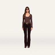 A woman stands against a plain white background, wearing sunglasses, the Elara Scoopneck Bodysuit—a long-sleeve brown stretch cotton modal piece that offers a body-contouring fit—paired with flared dark brown pants, a wide belt, and brown shoes.
