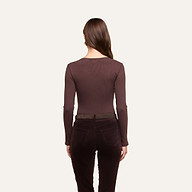 A woman with long brown hair, seen from behind, wears the Elara Scoopneck Bodysuit in a body-contouring fit along with dark brown pants against a plain off-white background.