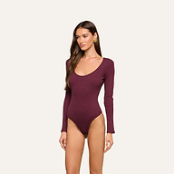 A woman wearing the Elara Scoopneck Bodysuit, made from stretch cotton modal for a body-contouring fit, stands against a plain light background, posing with one arm relaxed and her head turned slightly to the side.