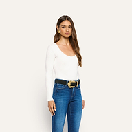 A person wearing an Elara Scoopneck Bodysuit tucked into blue jeans with a black belt featuring an ornate gold buckle.