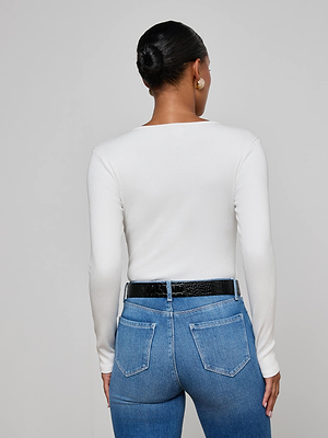 A woman wears the L'AGENCE Scarlet Scoopneck Tee, a white long-sleeve top with a scoop neckline.