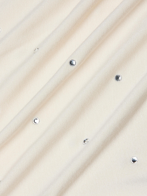 The Stormy Embellished Tee features cream-colored fabric with gentle diagonal folds and scattered small, round crystal embellishments, creating a subtle and elegant pattern.