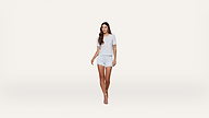 A woman with long brown hair wearing a light blue t-shirt, matching light blue shorts, and high-heeled sandals stands against a plain white background.