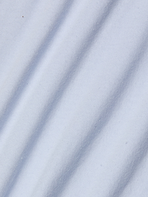 Close-up of light blue organic cotton fabric with diagonal folds and soft shadows—ideal for the Stormy Cropped Cotton Tee in a semi-relaxed fit.