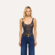 A woman with long blonde hair is wearing the Kalea Mesh Bodysuit—a sleeveless, sheer stretch scoop-neck style—paired with blue jeans and a black belt, standing against a plain light background.