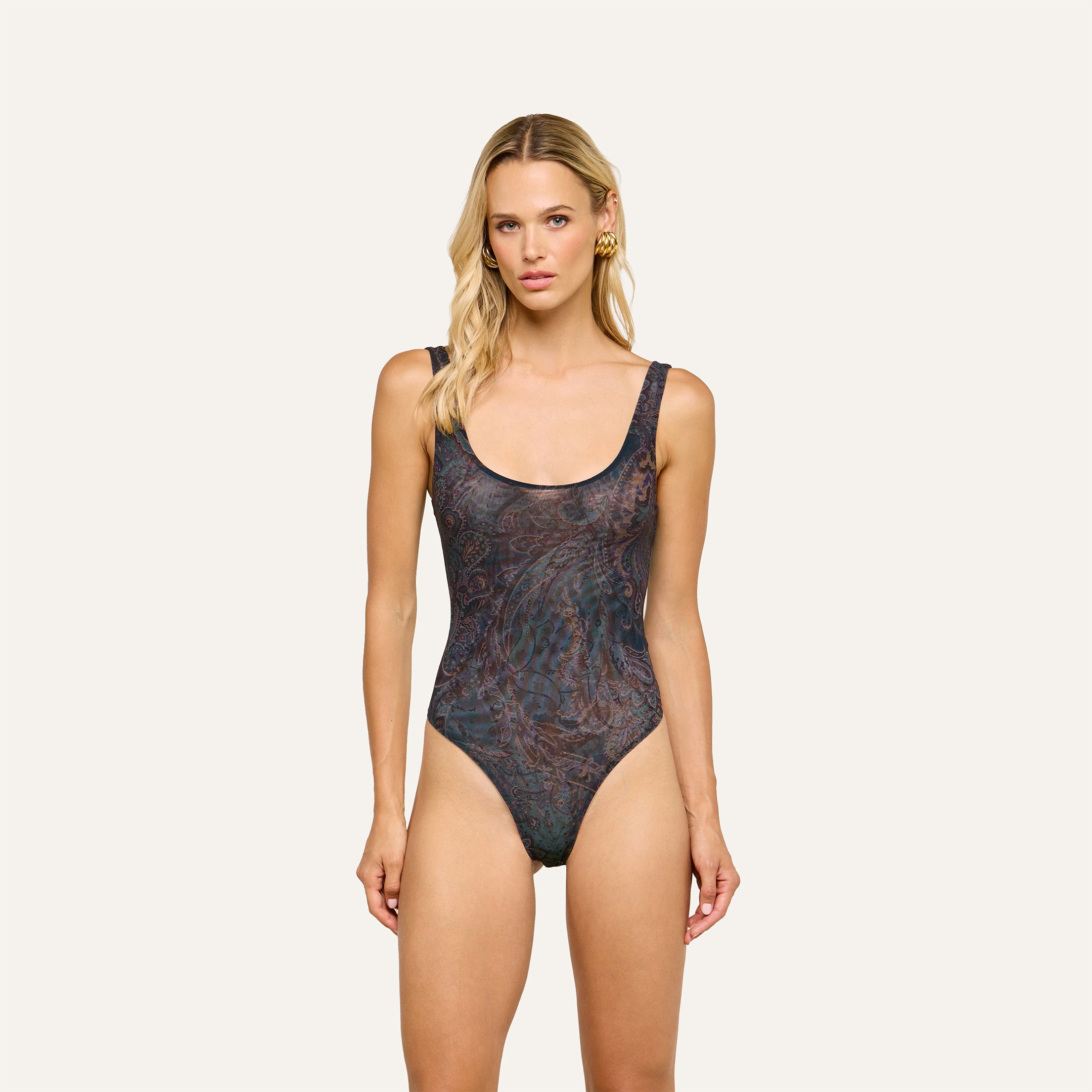 Woman with long blonde hair wearing the Kalea Mesh Bodysuit in midnight blue paisley stands facing forward against a plain light background.