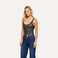 A woman with blonde hair wears the Kalea Mesh Bodysuit, featuring a sleeveless, semi-sheer patterned mesh design. She pairs it with high-waisted blue jeans, a black belt with a gold buckle, and gold earrings while standing against a plain light background.
