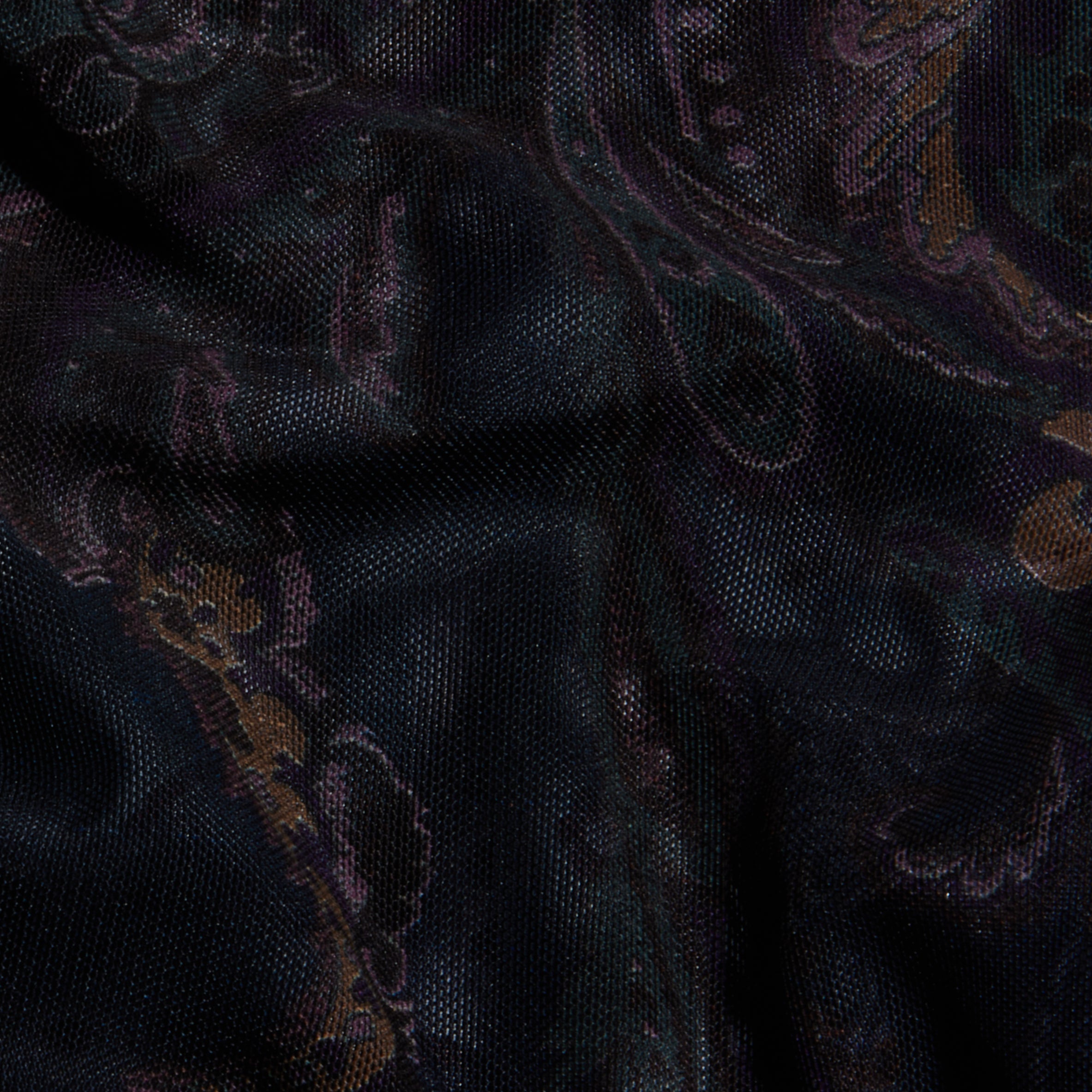 Close-up of the Kalea Mesh Bodysuit, featuring dark mesh fabric adorned with a subtle midnight blue paisley pattern in muted shades of brown, green, and purple, softly illuminated to highlight the texture and delicate folds.