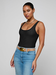A woman stands against a plain background, wearing the Kalea Mesh Bodysuit, blue jeans with a tan belt, and a gold chain necklace. Her hair is pulled back as she looks confidently at the camera.