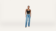 A woman stands against a plain white background, wearing a black tank top, blue jeans, a brown belt, and beige shoes.