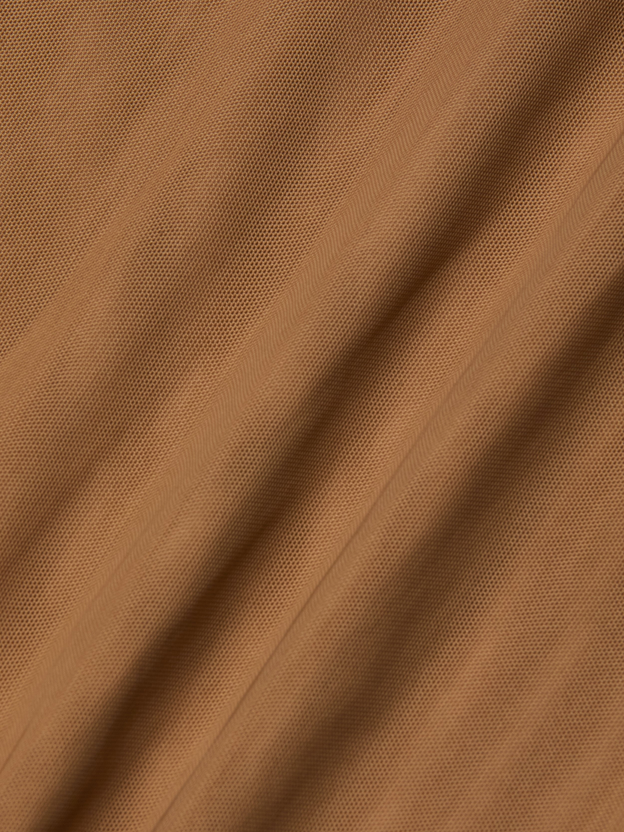 Close-up of light brown Kalea Mesh Bodysuit fabric with visible diagonal lines and subtle folds, creating a soft, rippled surface reminiscent of lightweight mesh.