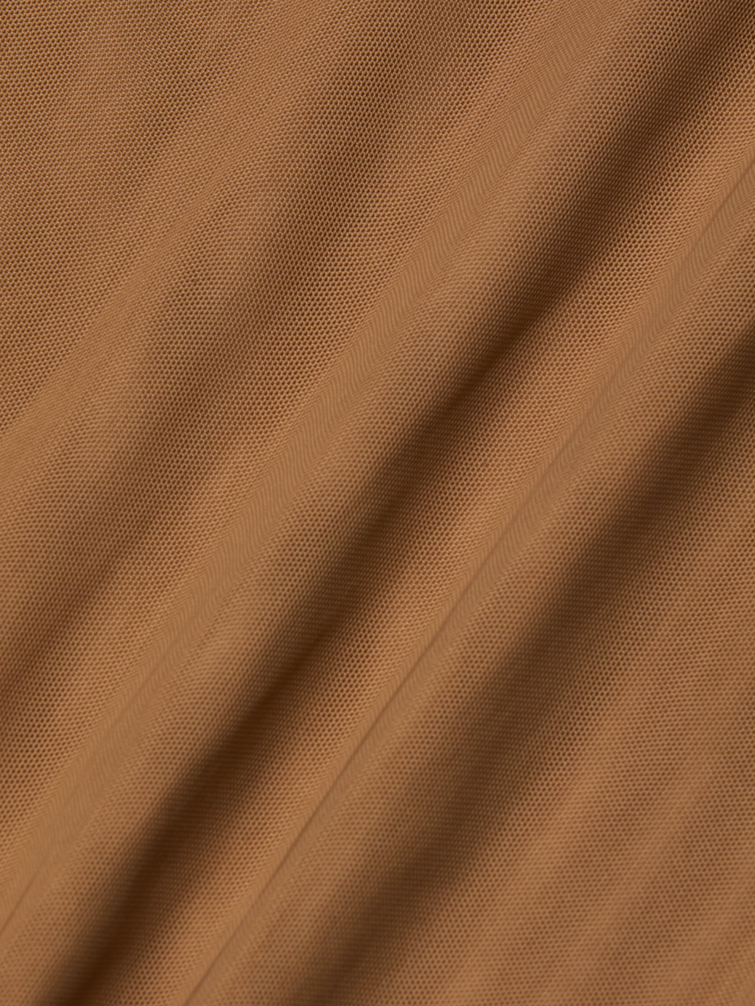 Close-up of light brown Kalea Mesh Bodysuit fabric with visible diagonal lines and subtle folds, creating a soft, rippled surface reminiscent of lightweight mesh.