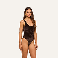 A woman is seen wearing the Kalea Velvet Bodysuit, featuring a sleeveless design and scoop neckline, set against a plain light background.