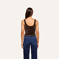 A person with long brown hair stands facing away, wearing the sleeveless dark brown Kalea Velvet Bodysuit and blue jeans against a plain light background.