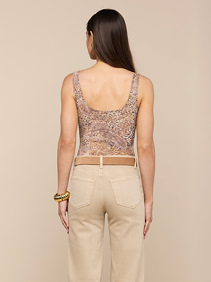 A woman with long brown hair, facing away, wears the Kalea Mesh Bodysuit—a sleeveless, semi-sheer patterned top—paired with high-waisted beige pocketed pants and a gold bracelet, set against a plain beige background.