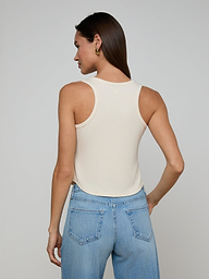 A woman stands with her back to the camera, wearing the Cael Tank Top in white and light blue jeans, set against a plain light background.