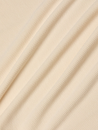 Beige ribbed fabric with diagonal folds, showcasing a subtle striped texture under soft, even lighting. Perfect for the Cael Tank Top, the material appears smooth, lightweight, and ultra soft—ideal for layering or wearing on its own.